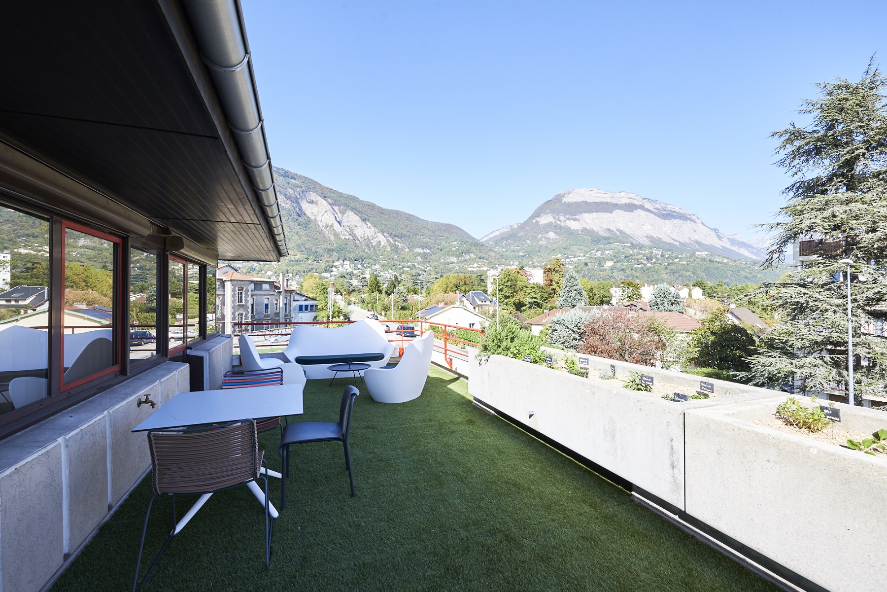 Une grande terrasse court le long de la façade et offre une vue imprenable sur les montagnes du mont Saint-Eynard.